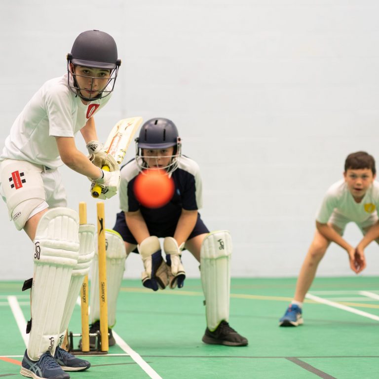 students playing cricket indoors
