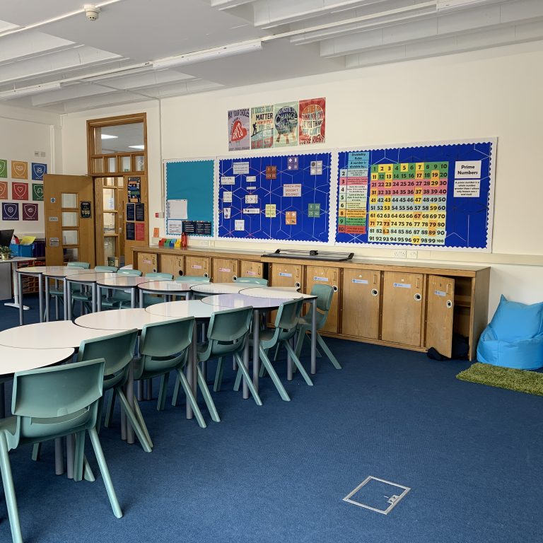 inside of a classroom with tables and chairs